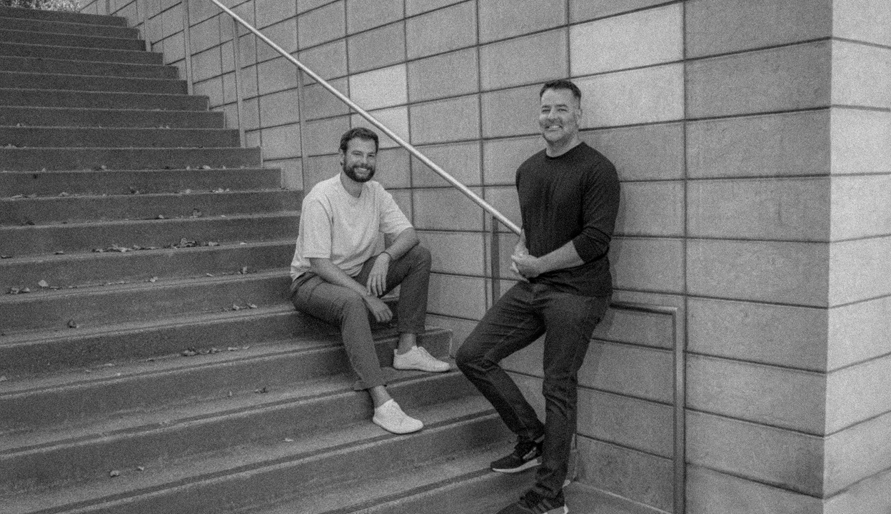 Jason Warner and Eiso Kant on a staircase, with friendly smiles. Eiso sits while Jason leans against the wall.